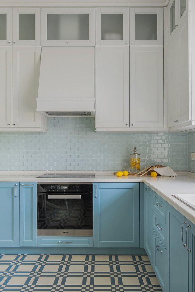 Пример оригинального дизайна: угловая кухня в стиле неоклассика (современная классика) с накладной мойкой, фасадами с утопленной филенкой, синими фасадами, техникой из нержавеющей стали, белой столешницей и двухцветным гарнитуром
