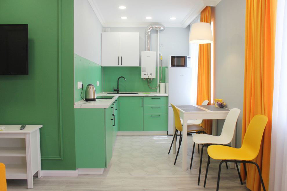 Photo of a small contemporary l-shaped kitchen/diner in Other with a built-in sink, flat-panel cabinets, green cabinets, green splashback, glass sheet splashback, integrated appliances, porcelain flooring, no island, grey floors and grey worktops.