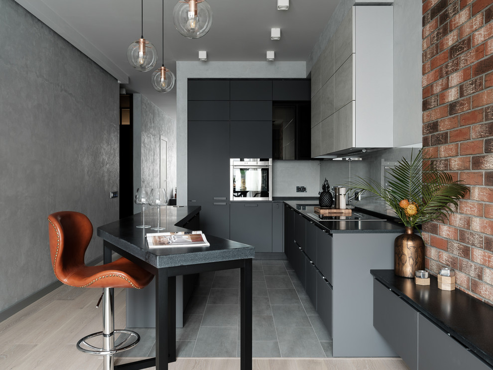 Immagine di una cucina industriale con ante lisce, ante grigie, paraspruzzi grigio, elettrodomestici in acciaio inossidabile, pavimento grigio, top nero e parquet e piastrelle
