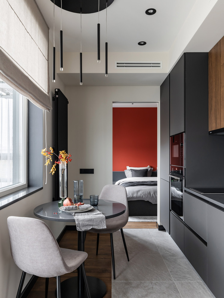 Immagine di una piccola cucina abitabile design con ante lisce, pavimento grigio, top grigio, ante grigie, elettrodomestici neri e parquet e piastrelle