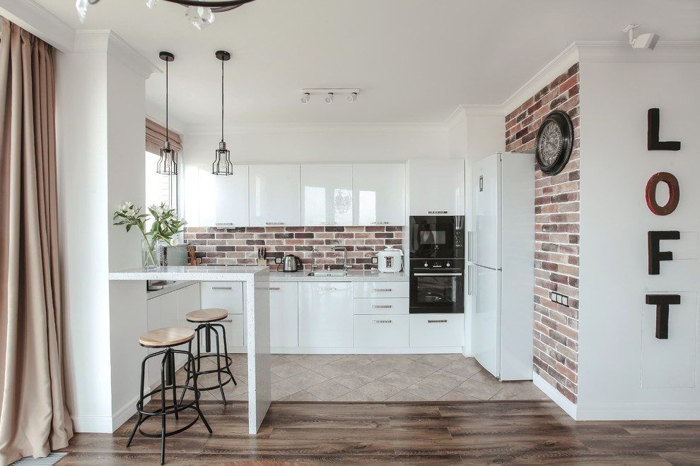 На фото: п-образная кухня-гостиная среднего размера в современном стиле с одинарной мойкой, плоскими фасадами, белыми фасадами, черной техникой и белой столешницей