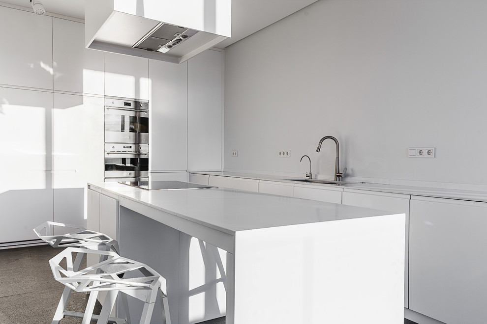 Diseño de cocina contemporánea de tamaño medio con armarios con paneles lisos, puertas de armario blancas, salpicadero blanco, electrodomésticos de acero inoxidable y una isla