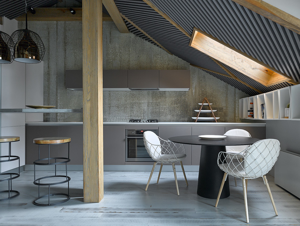 Immagine di una cucina design con ante lisce, ante grigie, paraspruzzi grigio, elettrodomestici in acciaio inossidabile e penisola