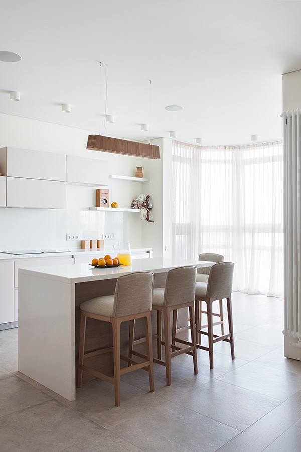 Стильный дизайн: прямая кухня-гостиная в современном стиле с плоскими фасадами, белыми фасадами, белым фартуком, фартуком из стекла и островом - последний тренд