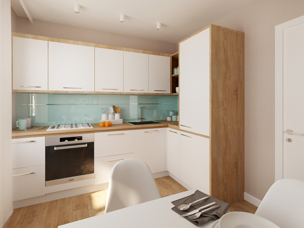 Photo of a small scandi l-shaped kitchen in Other with a built-in sink, flat-panel cabinets, white cabinets, wood worktops, glass sheet splashback, stainless steel appliances and ceramic flooring.