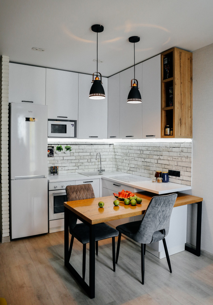 Foto de cocina contemporánea pequeña con fregadero encastrado, armarios con paneles lisos, puertas de armario blancas, salpicadero verde, salpicadero de azulejos de porcelana, electrodomésticos blancos, suelo laminado, península, suelo gris y encimeras blancas