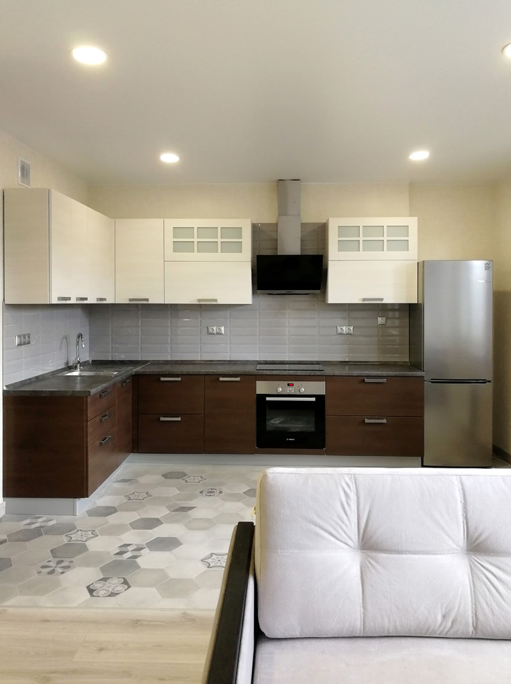 Inredning av ett minimalistiskt litet grå grått kök, med en undermonterad diskho, luckor med glaspanel, beige skåp, bänkskiva i betong, grått stänkskydd, stänkskydd i keramik, rostfria vitvaror, klinkergolv i porslin, en halv köksö och grått golv