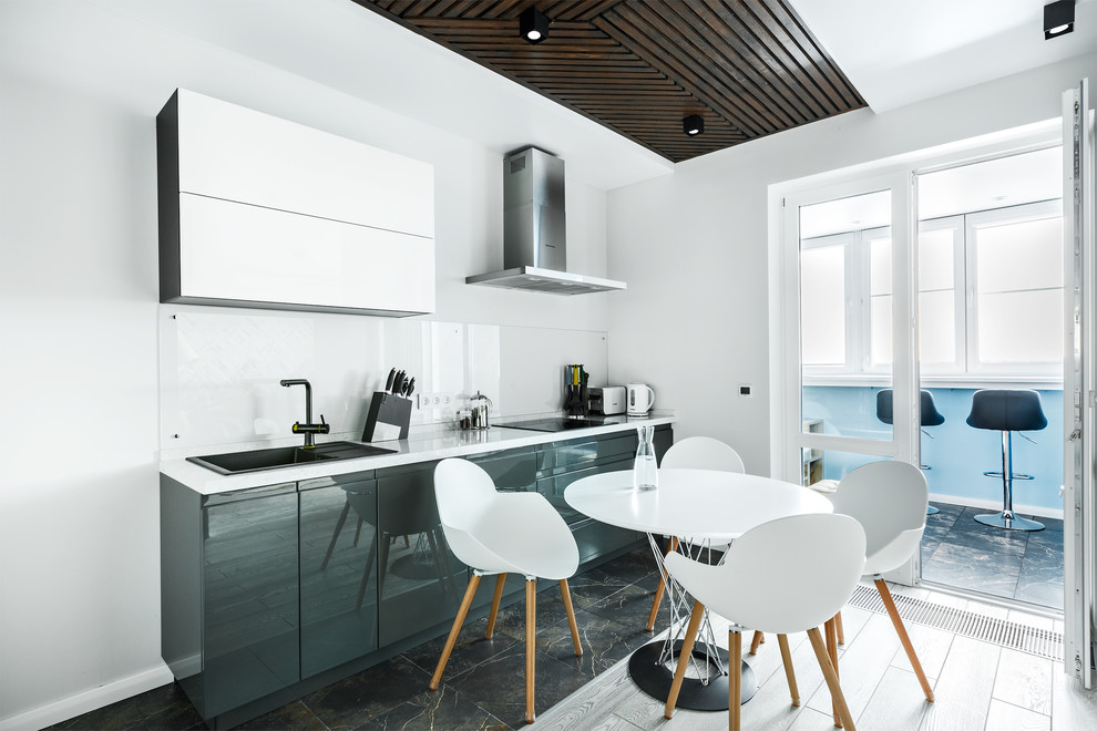 Идея дизайна: прямая кухня в современном стиле с обеденным столом, накладной мойкой, плоскими фасадами, белым фартуком и фартуком из стекла без острова