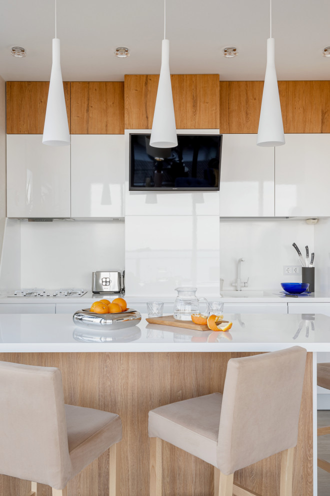Moderne Küche mit flächenbündigen Schrankfronten, weißen Schränken, Küchenrückwand in Weiß, Kücheninsel und weißer Arbeitsplatte in Sonstige