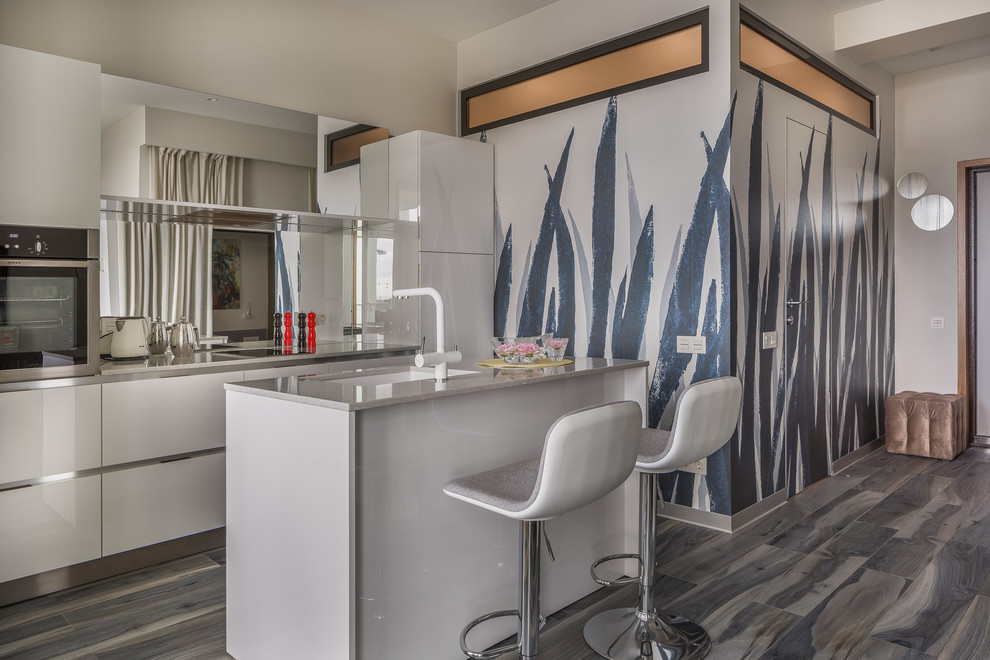 Scandinavian open plan kitchen in Other with a submerged sink, flat-panel cabinets, white cabinets, an island, mirror splashback, brown floors and grey worktops.