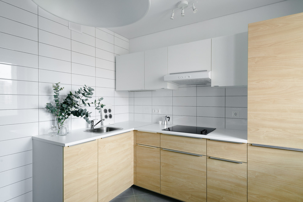 Inredning av ett minimalistiskt avskilt l-kök, med en nedsänkt diskho, släta luckor och vitt stänkskydd