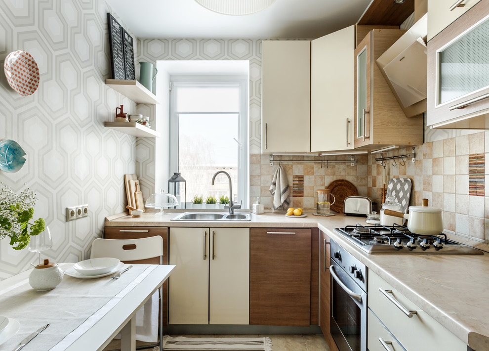 Enclosed kitchen - contemporary l-shaped beige floor enclosed kitchen idea in Other with a drop-in sink, flat-panel cabinets, beige cabinets, beige backsplash, black appliances, no island, beige countertops and window backsplash