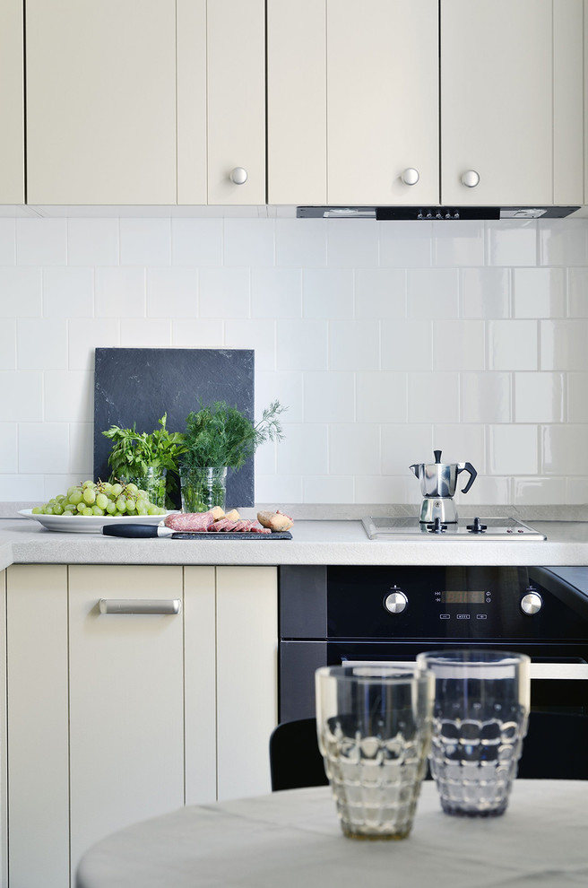 Ejemplo de cocina contemporánea abierta con armarios con paneles lisos, puertas de armario blancas, salpicadero blanco y electrodomésticos negros