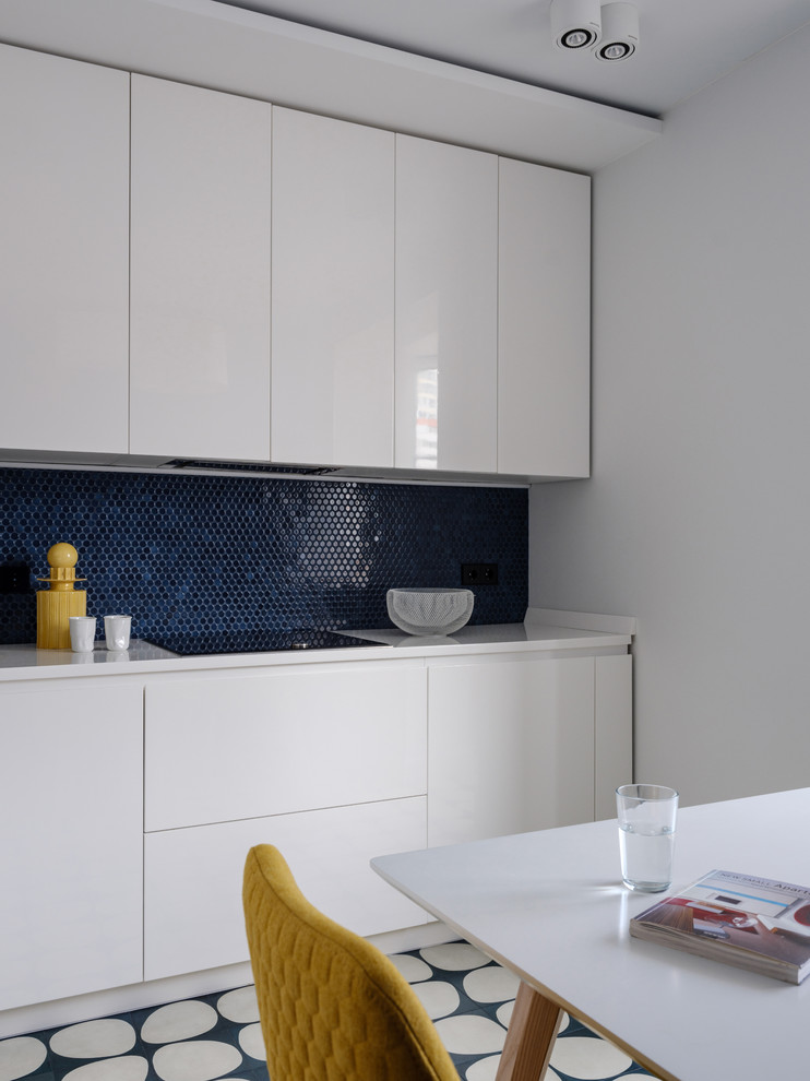 Cette photo montre une cuisine tendance avec des portes de placard blanches, une crédence bleue, une crédence en mosaïque, aucun îlot et un plan de travail blanc.