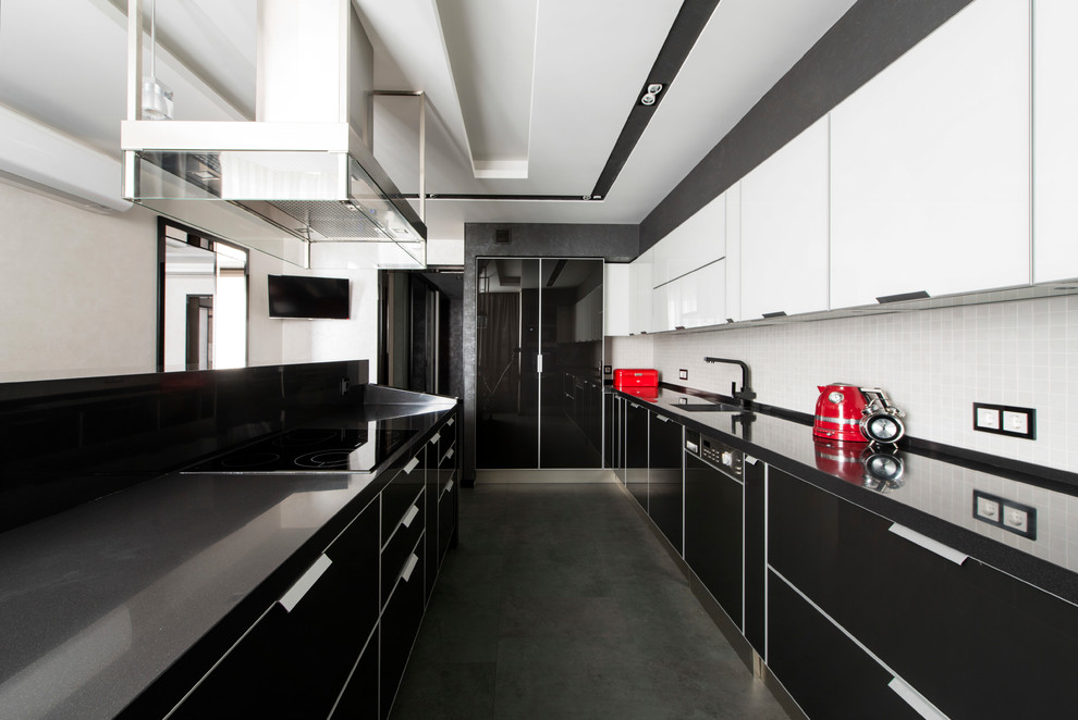 На фото: п-образная кухня в современном стиле с врезной мойкой, плоскими фасадами, белым фартуком, островом, черным полом и черной столешницей с