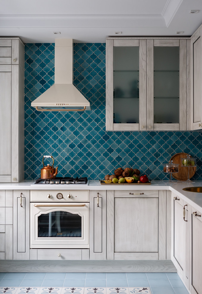 Inspiration for a mid-sized transitional l-shaped ceramic tile and turquoise floor eat-in kitchen remodel in Moscow with raised-panel cabinets, light wood cabinets, solid surface countertops, blue backsplash, ceramic backsplash, white appliances, no island and a drop-in sink