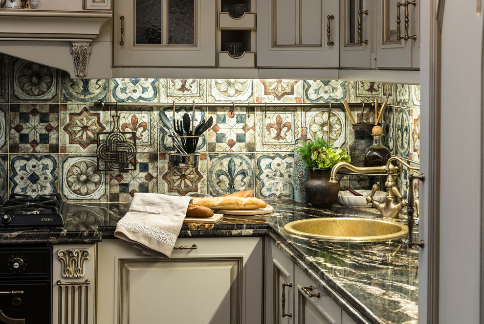 Mid-sized elegant l-shaped eat-in kitchen photo in Moscow with a drop-in sink, raised-panel cabinets, beige cabinets, marble countertops, beige backsplash, porcelain backsplash, black appliances and no island