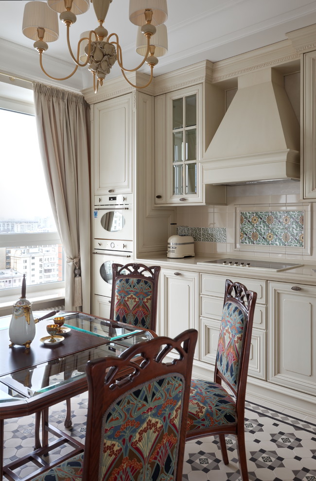 Inredning av ett klassiskt kök, med luckor med upphöjd panel, beige skåp, beige stänkskydd, vita vitvaror, klinkergolv i keramik och flerfärgat golv