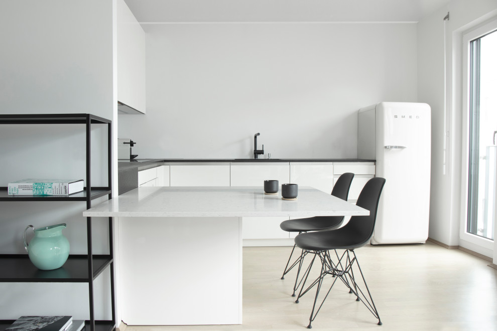Skandinavisk inredning av ett mellanstort grå grått kök, med vita skåp, en integrerad diskho, släta luckor, en halv köksö och beiget golv
