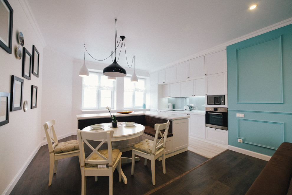 Cette photo montre une cuisine ouverte linéaire tendance de taille moyenne avec un placard avec porte à panneau encastré, des portes de placard blanches, un électroménager noir et îlot.