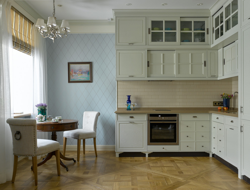 Idéer för ett klassiskt kök, med luckor med infälld panel, beige stänkskydd, rostfria vitvaror, mellanmörkt trägolv, en undermonterad diskho och vita skåp