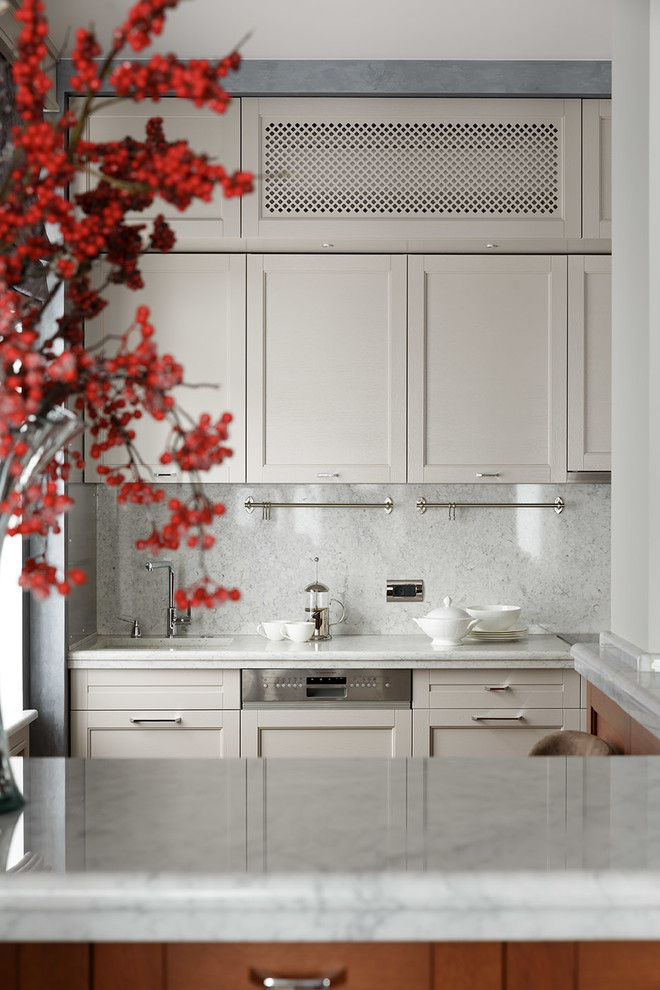 Свежая идея для дизайна: прямая кухня-гостиная в стиле неоклассика (современная классика) с белыми фасадами, техникой под мебельный фасад и врезной мойкой - отличное фото интерьера