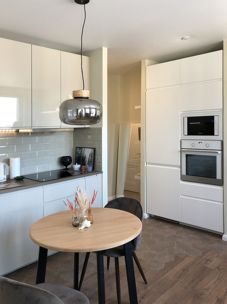 Идея дизайна: маленькая прямая кухня-гостиная в скандинавском стиле с врезной мойкой, плоскими фасадами, белыми фасадами, белым фартуком, двумя и более островами и коричневым полом для на участке и в саду