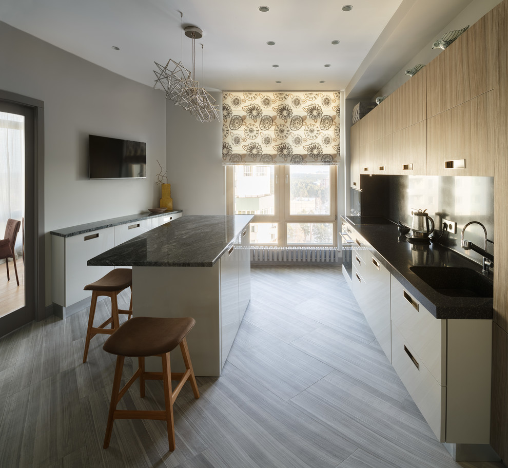На фото: отдельная, прямая кухня в современном стиле с плоскими фасадами, островом, серым полом и черной столешницей