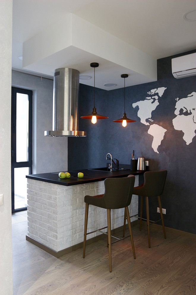 Imagen de cocina contemporánea pequeña abierta con encimera de granito, salpicadero negro, electrodomésticos de acero inoxidable, suelo de madera en tonos medios y península