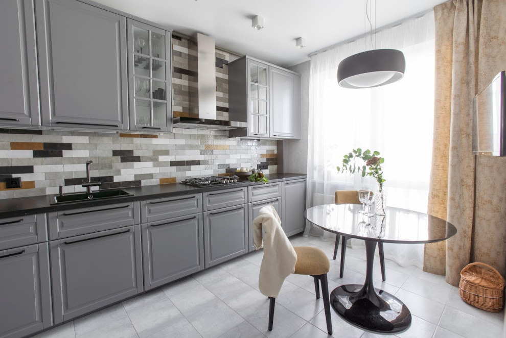 Inspiration for a mid-sized single-wall porcelain tile and gray floor enclosed kitchen remodel in Saint Petersburg with a drop-in sink, gray cabinets, laminate countertops, multicolored backsplash, ceramic backsplash, black countertops and black appliances