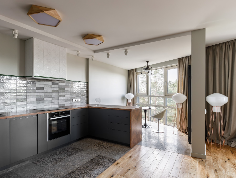 На фото: п-образная кухня-гостиная в современном стиле с врезной мойкой, серыми фасадами, серым фартуком и фартуком из керамической плитки без острова