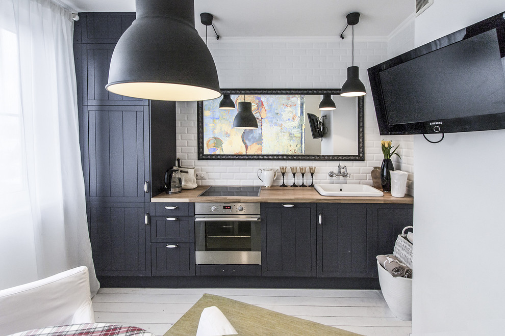 Photo of a scandi single-wall enclosed kitchen in Moscow with a built-in sink, black cabinets, wood worktops, white splashback, metro tiled splashback, stainless steel appliances, no island and white floors.