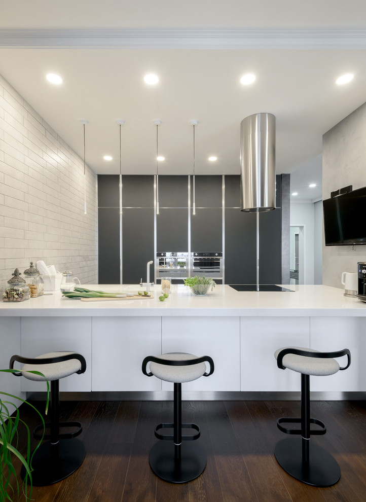 На фото: параллельная кухня-гостиная в современном стиле с плоскими фасадами, темным паркетным полом, островом и черно-белыми фасадами
