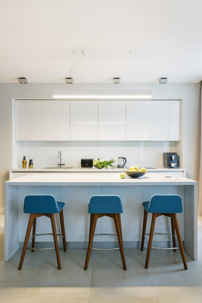 Foto de cocina lineal contemporánea abierta con fregadero de un seno, armarios con paneles lisos, puertas de armario blancas, salpicadero blanco, una isla y suelo beige