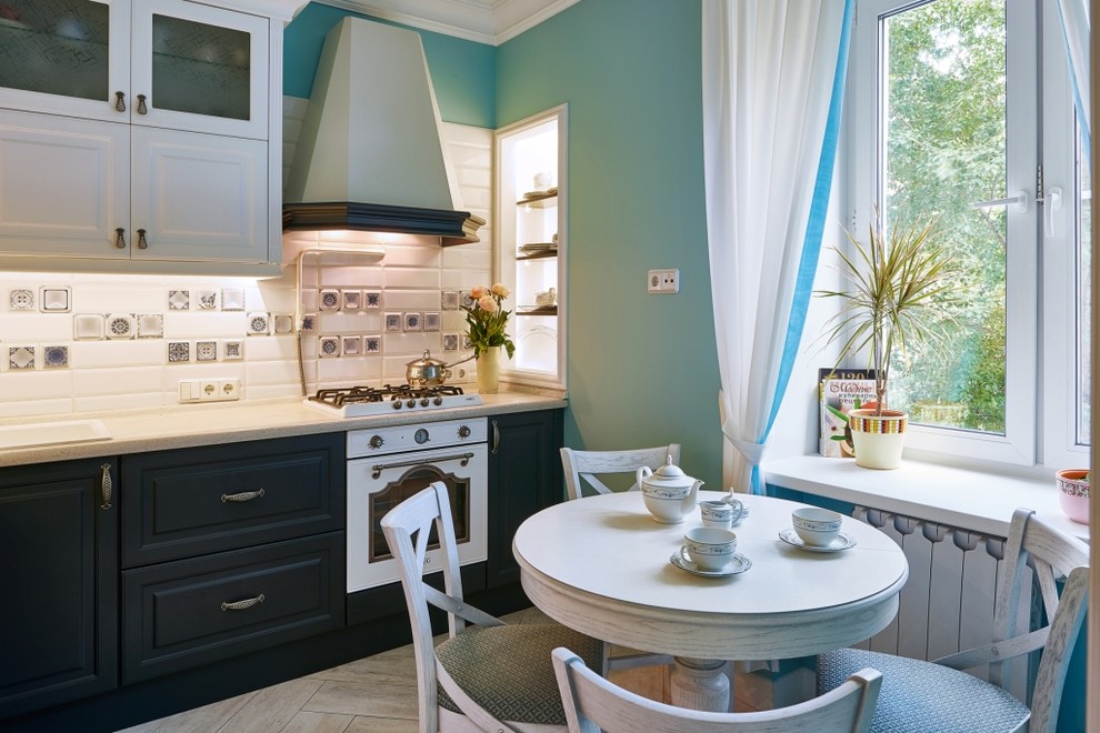 Modern inredning av ett mellanstort kök, med en nedsänkt diskho, luckor med upphöjd panel, blå skåp, laminatbänkskiva, vitt stänkskydd, vita vitvaror och klinkergolv i porslin