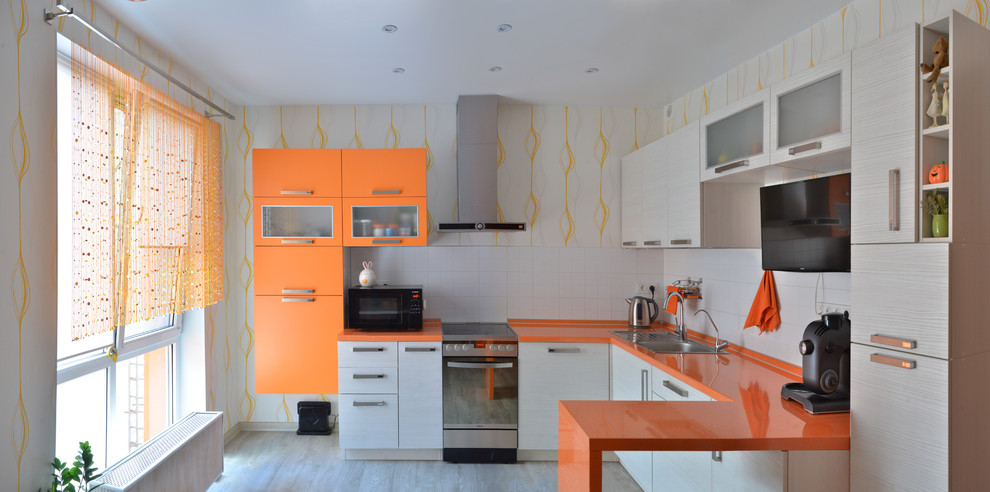 モスクワにある低価格の中くらいなコンテンポラリースタイルのおしゃれなキッチン (ドロップインシンク、フラットパネル扉のキャビネット、白いキャビネット、白いキッチンパネル、シルバーの調理設備、グレーの床、オレンジのキッチンカウンター、壁紙) の写真