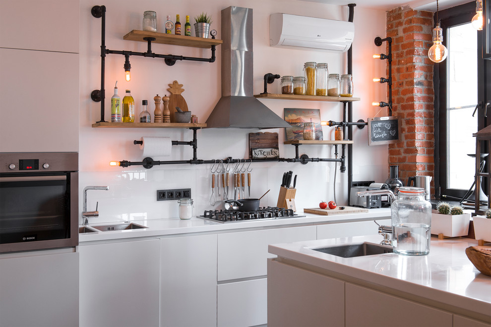 This is an example of a medium sized industrial single-wall open plan kitchen in Moscow with a submerged sink, flat-panel cabinets, white cabinets, composite countertops, white splashback, glass sheet splashback, stainless steel appliances, laminate floors, an island and brown floors.