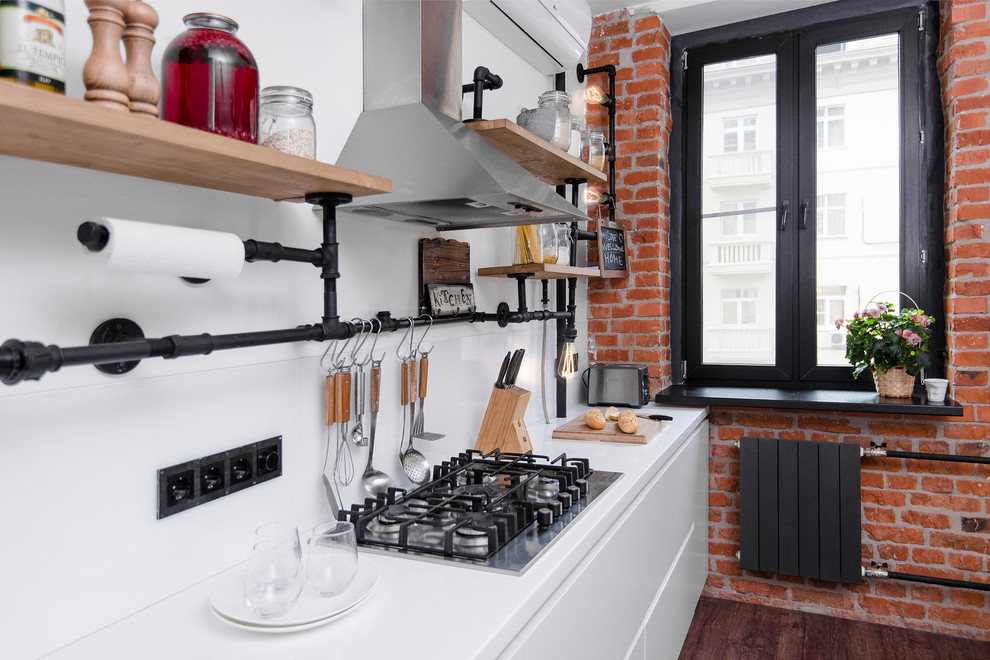 Mid-sized urban single-wall laminate floor and brown floor open concept kitchen photo in Moscow with an undermount sink, flat-panel cabinets, white cabinets, solid surface countertops, white backsplash, glass sheet backsplash, stainless steel appliances and an island