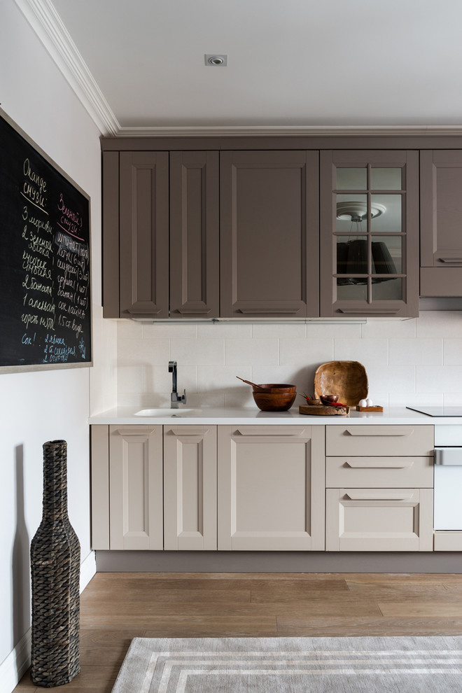 Immagine di una cucina chic con ante con riquadro incassato, ante beige, paraspruzzi bianco, pavimento marrone e top bianco