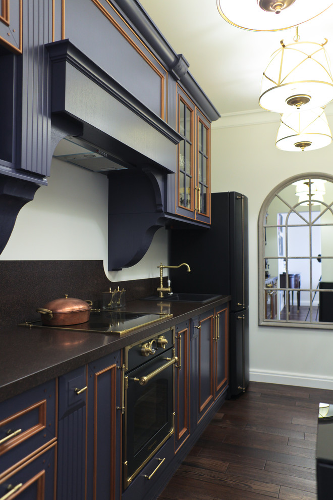 Foto de cocina tradicional con fregadero encastrado, electrodomésticos negros, suelo de madera oscura, armarios con rebordes decorativos y puertas de armario azules