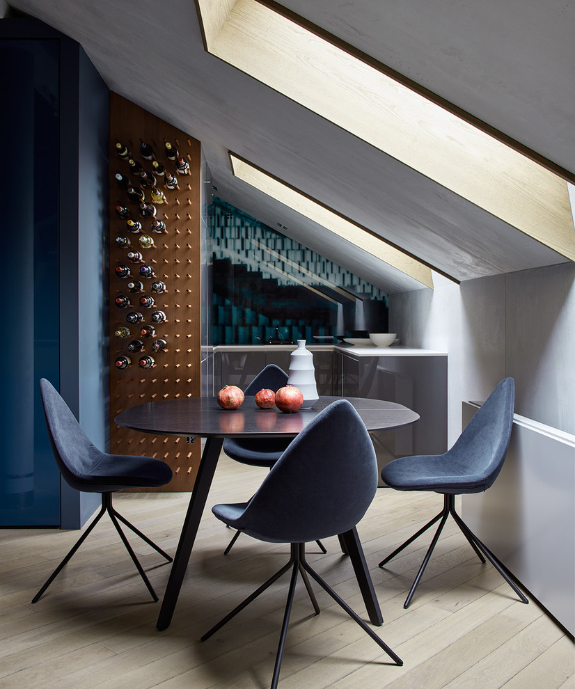 Moderne Küche mit hellem Holzboden, flächenbündigen Schrankfronten und grauen Schränken in Sonstige