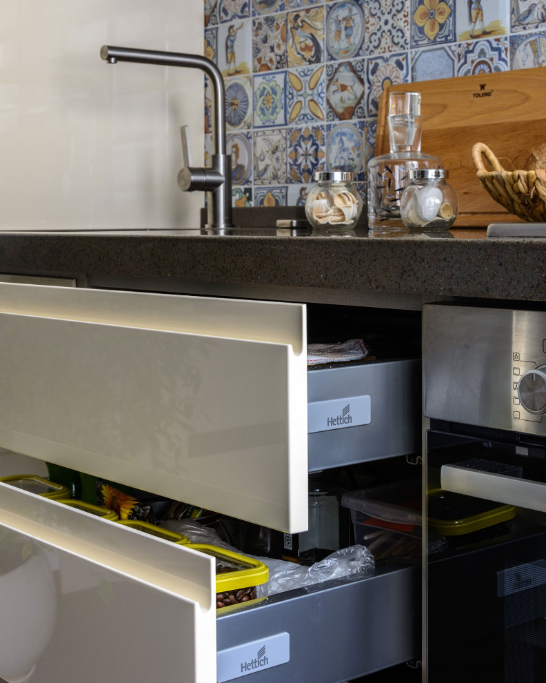 Bild på ett mellanstort funkis brun linjärt brunt kök och matrum, med en integrerad diskho, släta luckor, beige skåp, bänkskiva i koppar, flerfärgad stänkskydd, stänkskydd i mosaik, svarta vitvaror och brunt golv