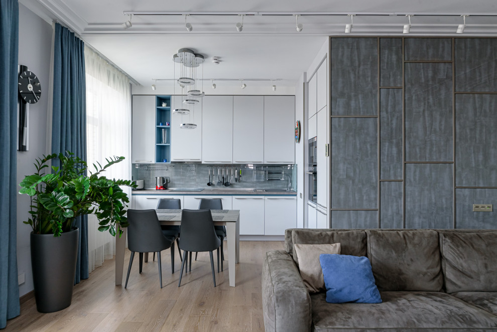 Идея дизайна: угловая кухня-гостиная в современном стиле с плоскими фасадами, серыми фасадами, паркетным полом среднего тона, коричневым полом и серой столешницей без острова