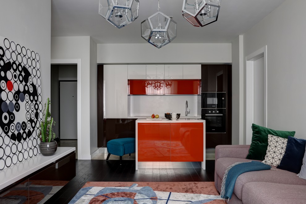Modelo de cocina lineal contemporánea abierta con armarios con paneles lisos, puertas de armario rojas, salpicadero blanco, una isla y encimeras blancas