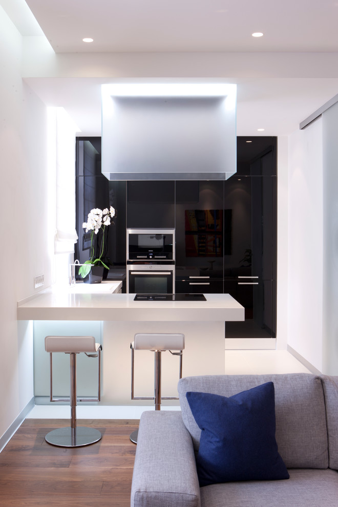 Diseño de cocina contemporánea pequeña abierta con armarios con paneles lisos, electrodomésticos de acero inoxidable, península y con blanco y negro