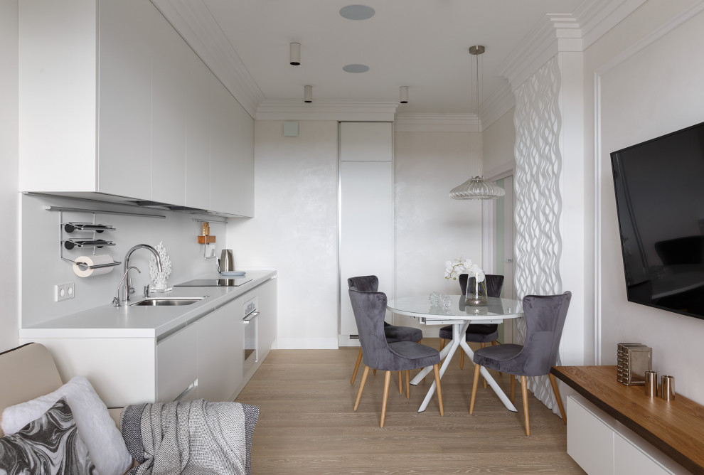Eat-in kitchen - contemporary single-wall light wood floor and beige floor eat-in kitchen idea in Saint Petersburg with an undermount sink, flat-panel cabinets, white cabinets, white backsplash, stainless steel appliances, no island and white countertops