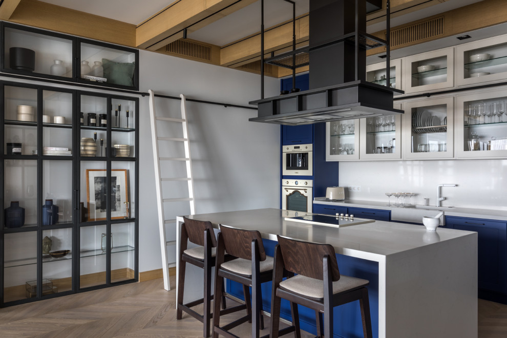 Exempel på ett industriellt vit linjärt vitt kök, med luckor med glaspanel, vitt stänkskydd, rostfria vitvaror, ljust trägolv, en köksö, en rustik diskho, blå skåp och beiget golv