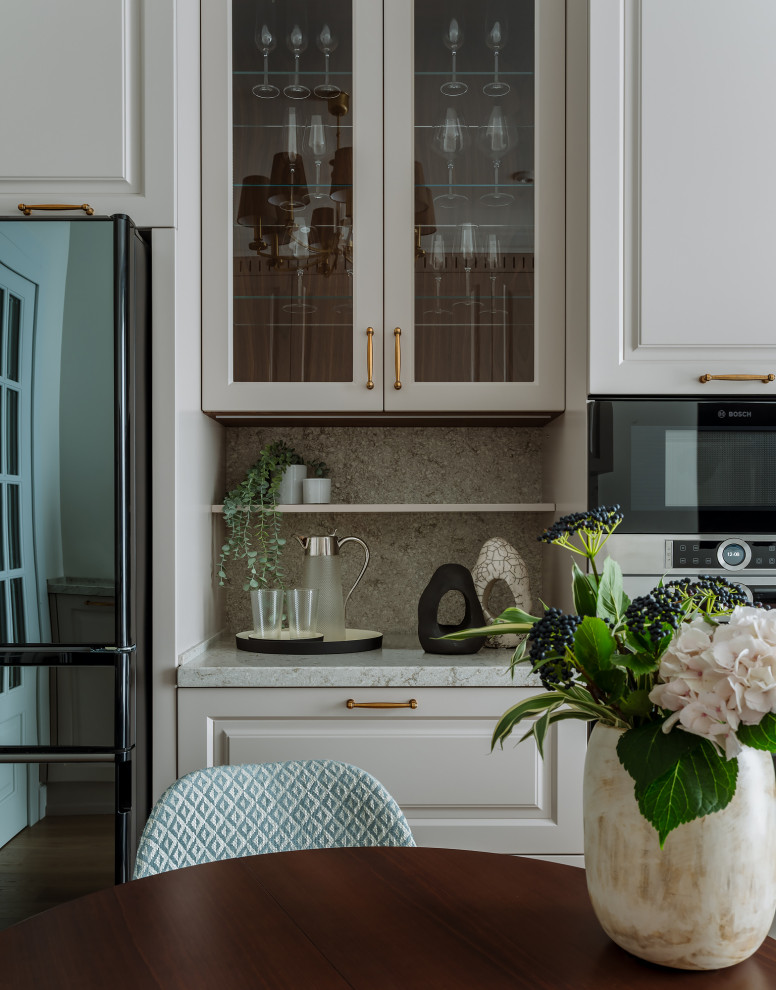 Klassisk inredning av ett litet grå grått kök, med en undermonterad diskho, luckor med upphöjd panel, beige skåp, bänkskiva i kvarts, grått stänkskydd, svarta vitvaror, mellanmörkt trägolv och brunt golv