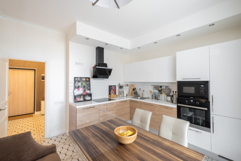 Photo of a medium sized contemporary l-shaped kitchen/diner in Saint Petersburg with a built-in sink, flat-panel cabinets, beige cabinets, composite countertops, white splashback, metro tiled splashback, integrated appliances, porcelain flooring, no island, beige floors and white worktops.