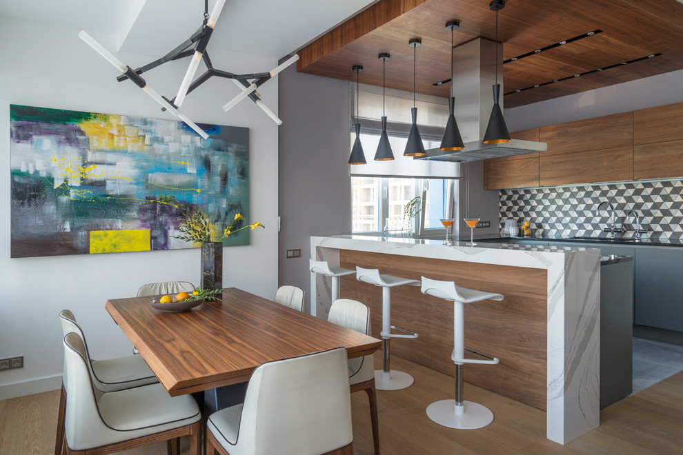 На фото: прямая кухня-гостиная в современном стиле с плоскими фасадами, фасадами цвета дерева среднего тона, разноцветным фартуком и островом с